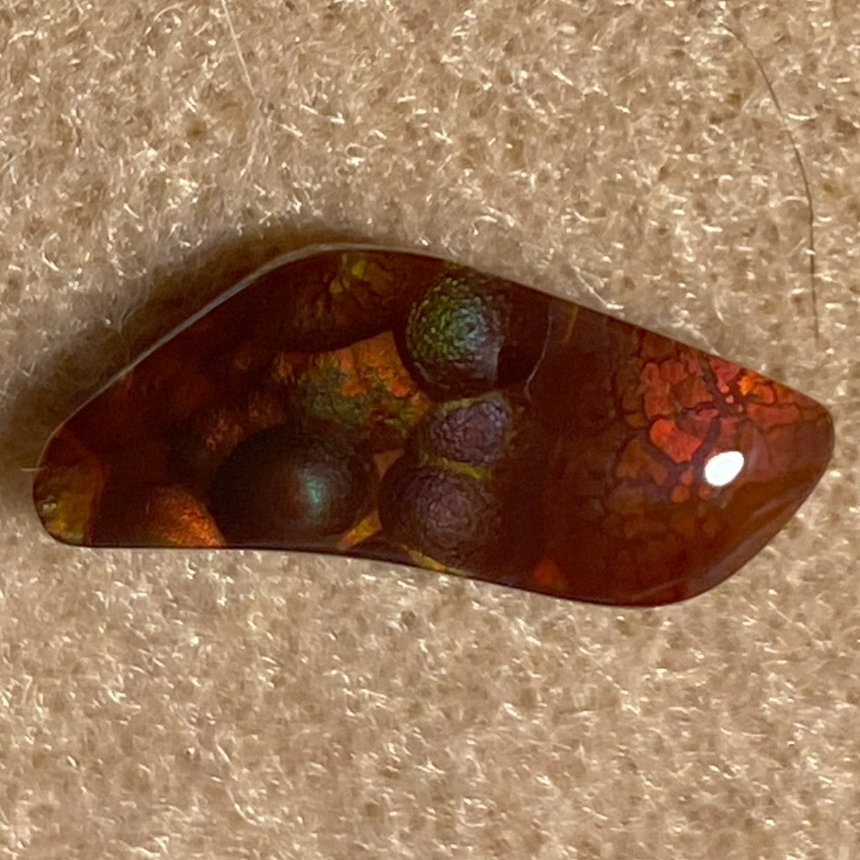 Multicolored Fire Agate Gemstone on a textured beige background