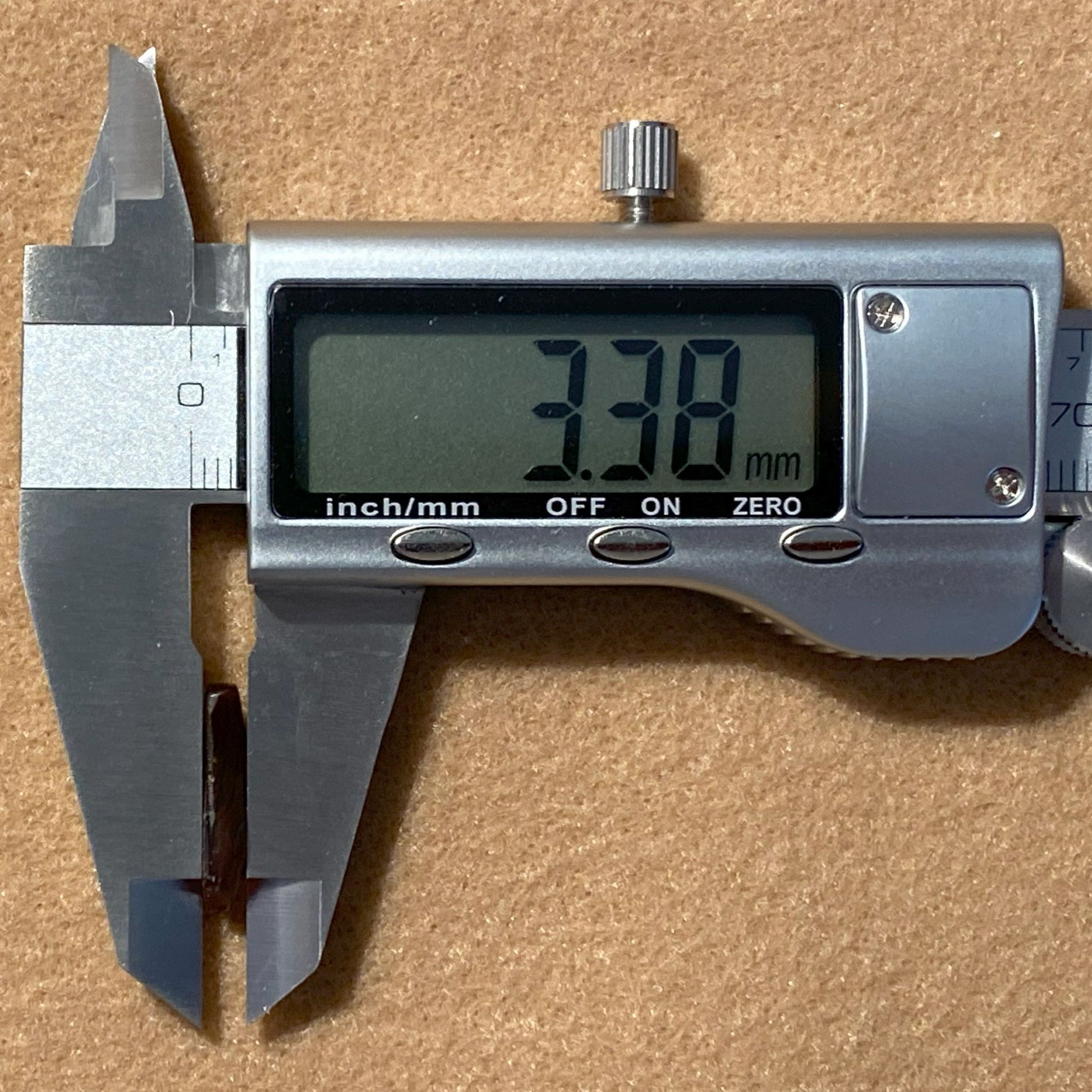 Digital caliper showing a measurement of 3.38 mm on a brown background