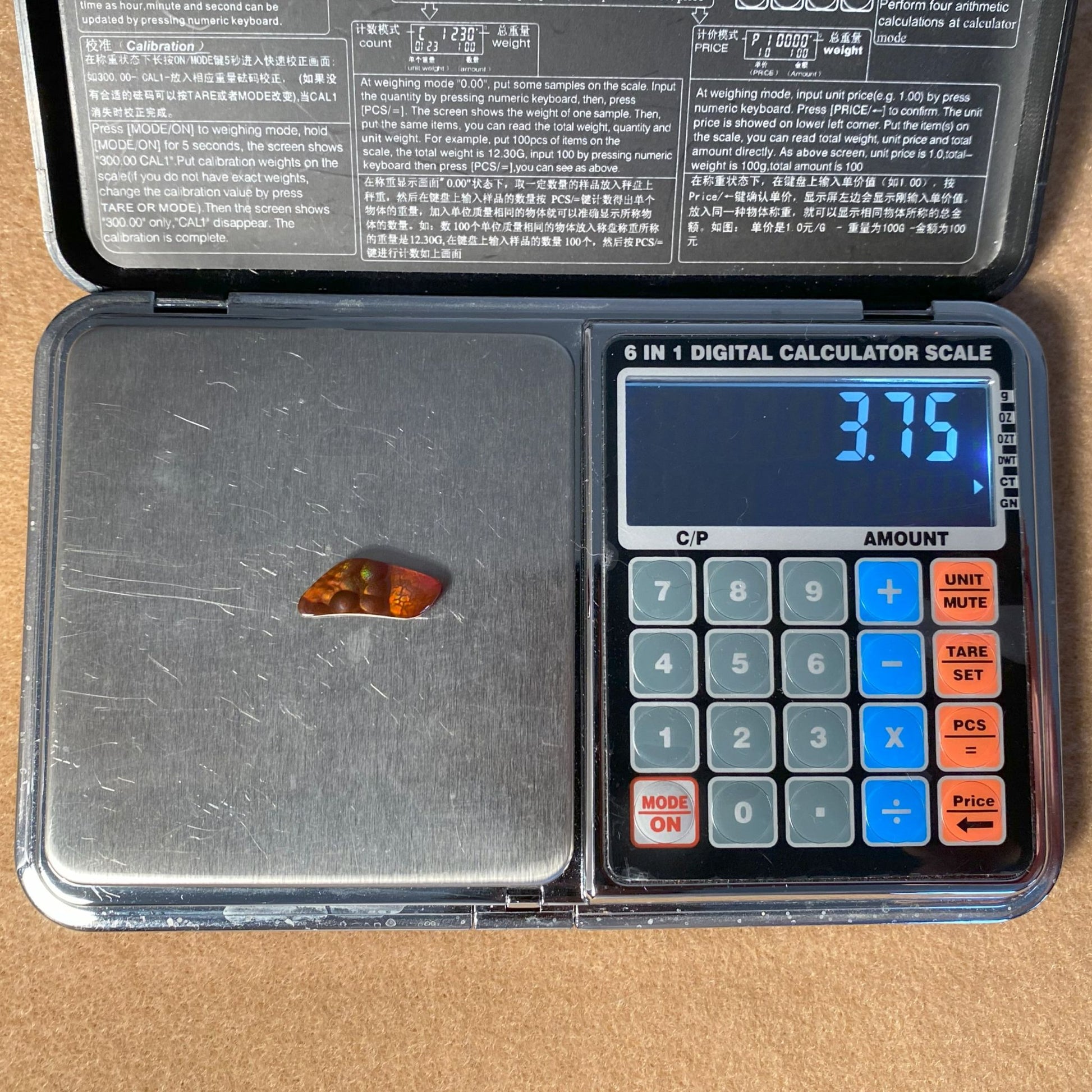 Digital calculator scale with a Fire Agate Gemstone on a beige surface