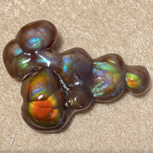 Multicolored Aguascalientes Fire Agate Gemstone with iridescent sheen on a beige background
