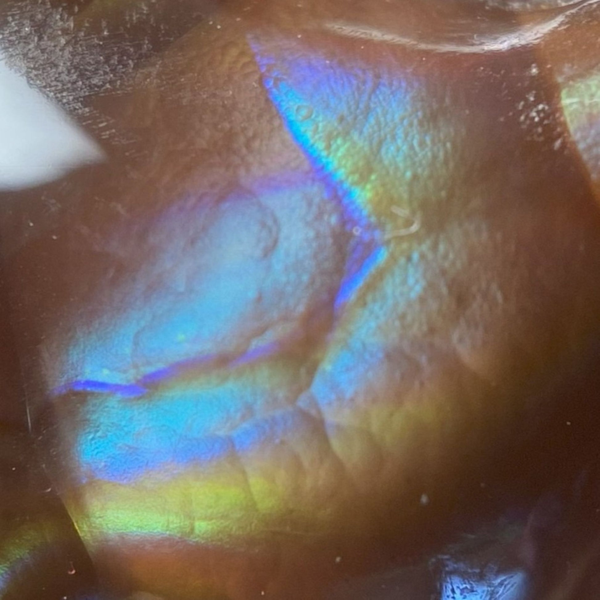 Close-up of a colorful, iridescent Aguascalientes Fire Agate Gemstone with a textured surface.