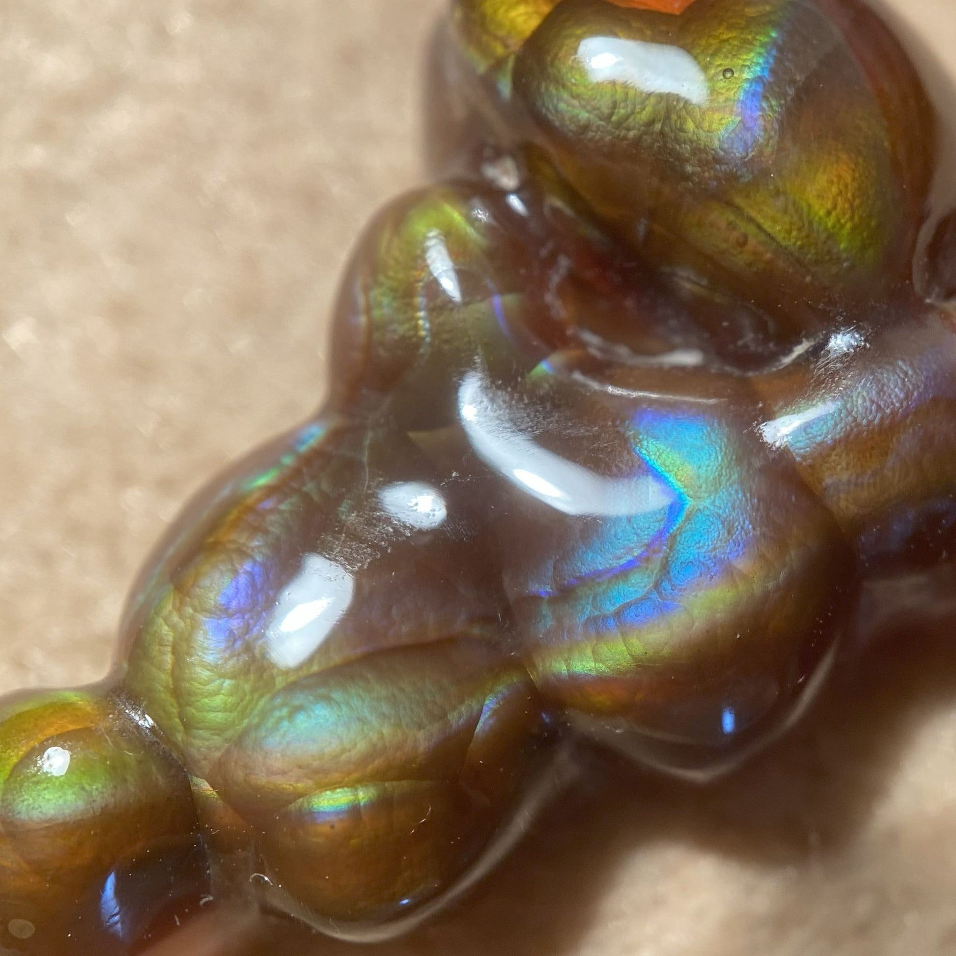 Close-up of an iridescent Aguascalientes Fire Agate Gemstone on a beige background
