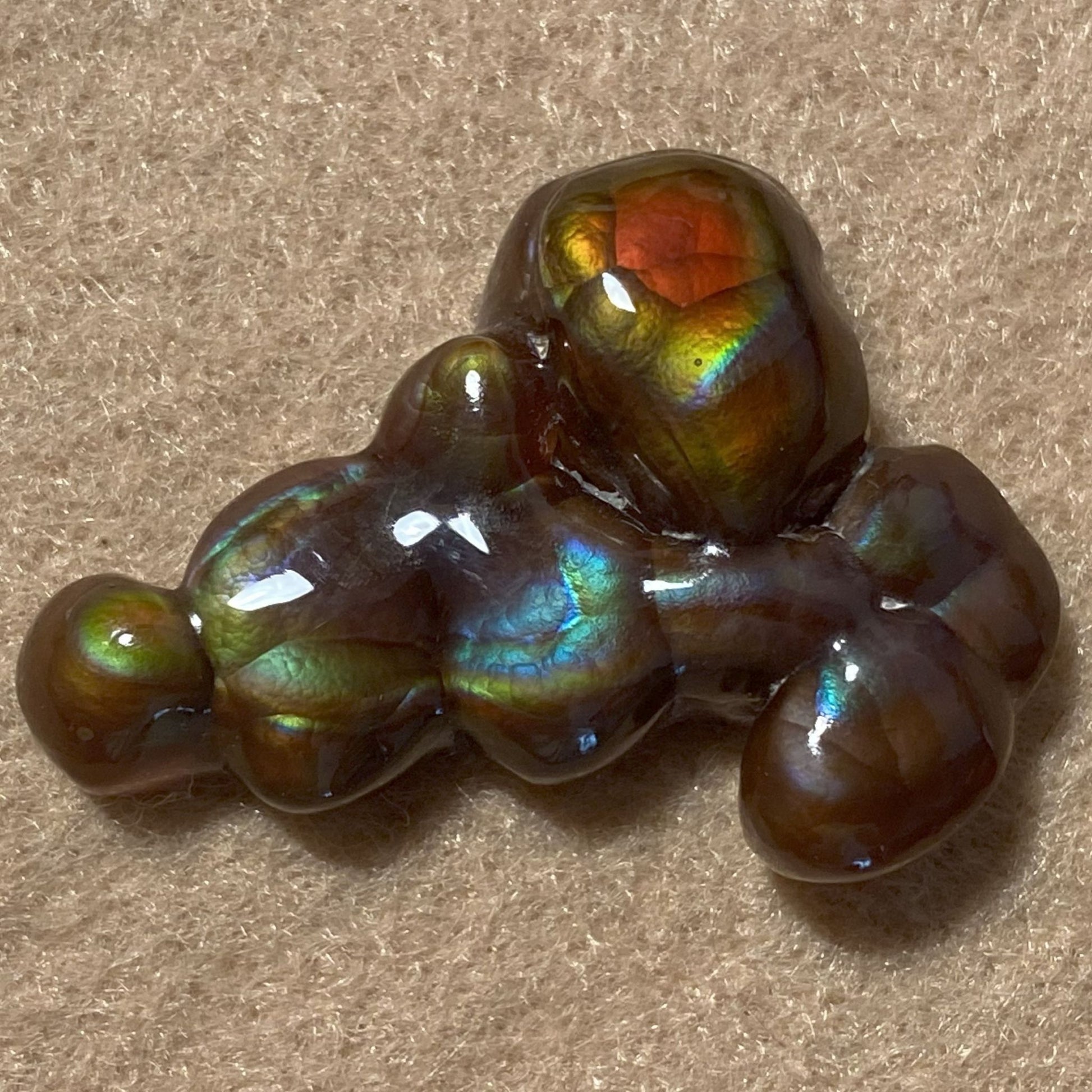 Iridescent Aguascalientes Fire Agate Gemstone on a beige background