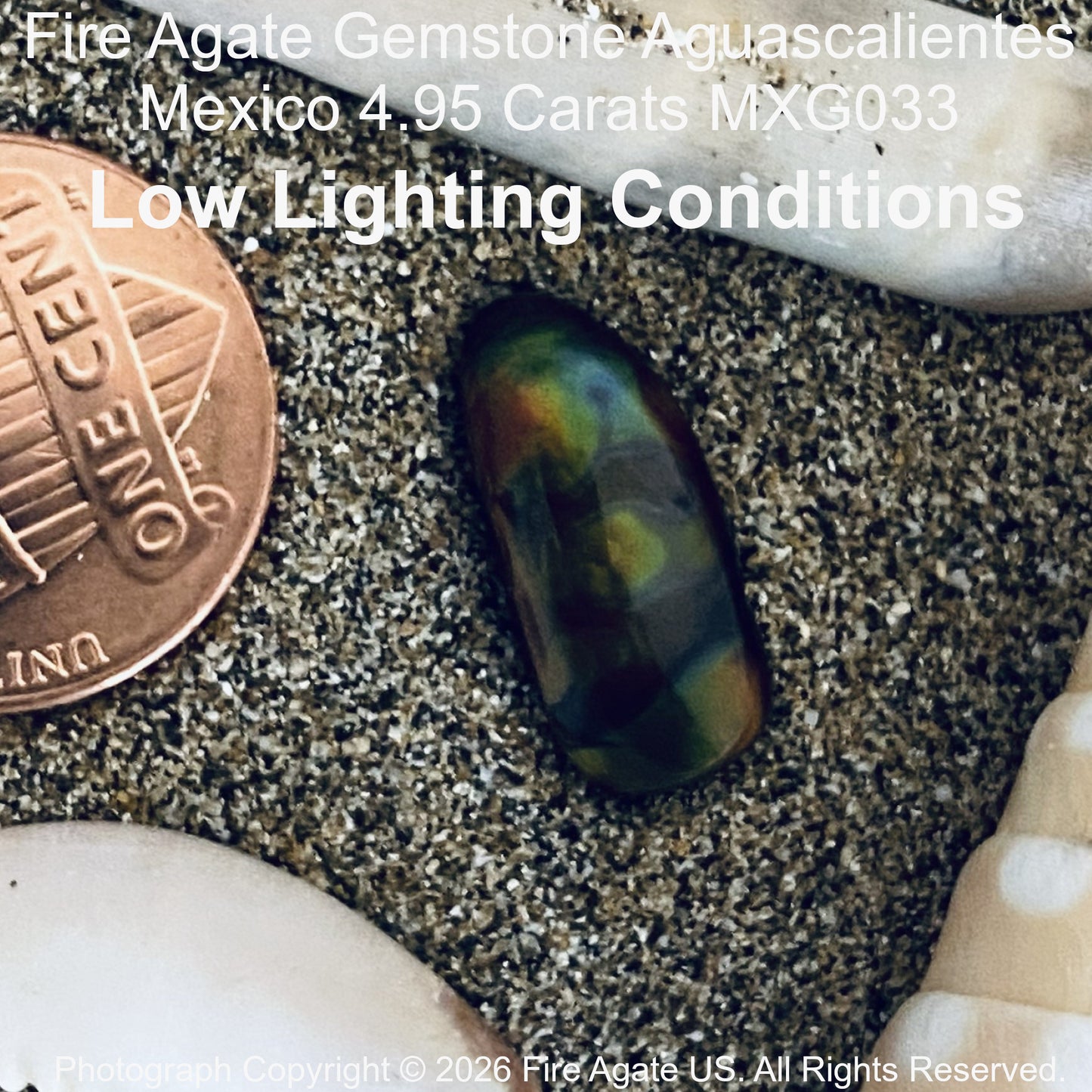 A 4.95 carat Fire Agate gemstone shown in low light conditions, displayed on sand next to a penny for scale and seashells.