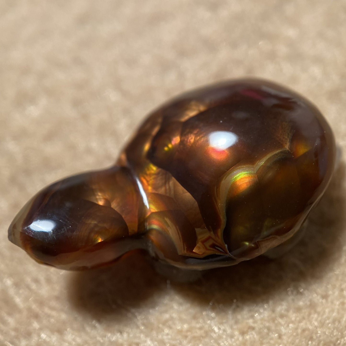 Polished Aguascalientes Fire Agate Creature Carving Charm Specimen on a beige background
