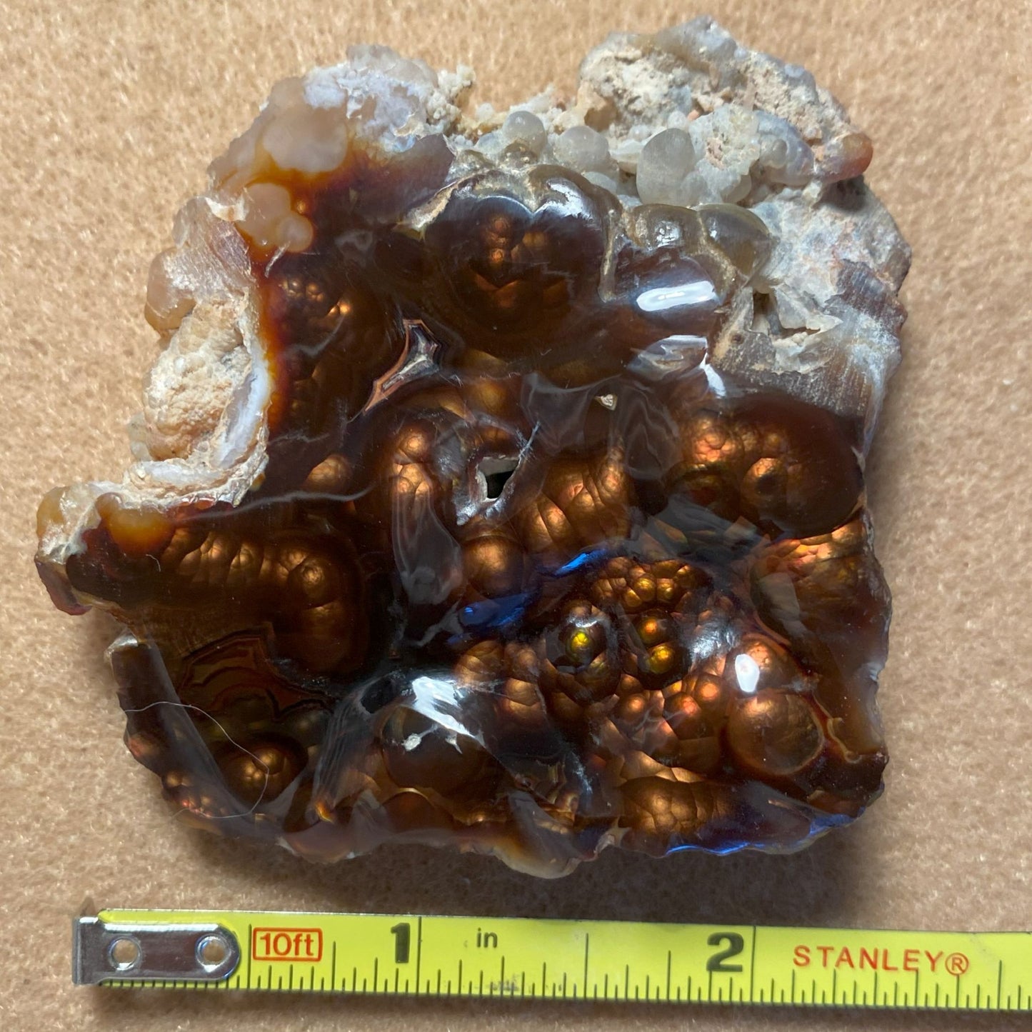 Aguascalientes Fire Agate Rough stone with a measuring tape for scale on a beige background