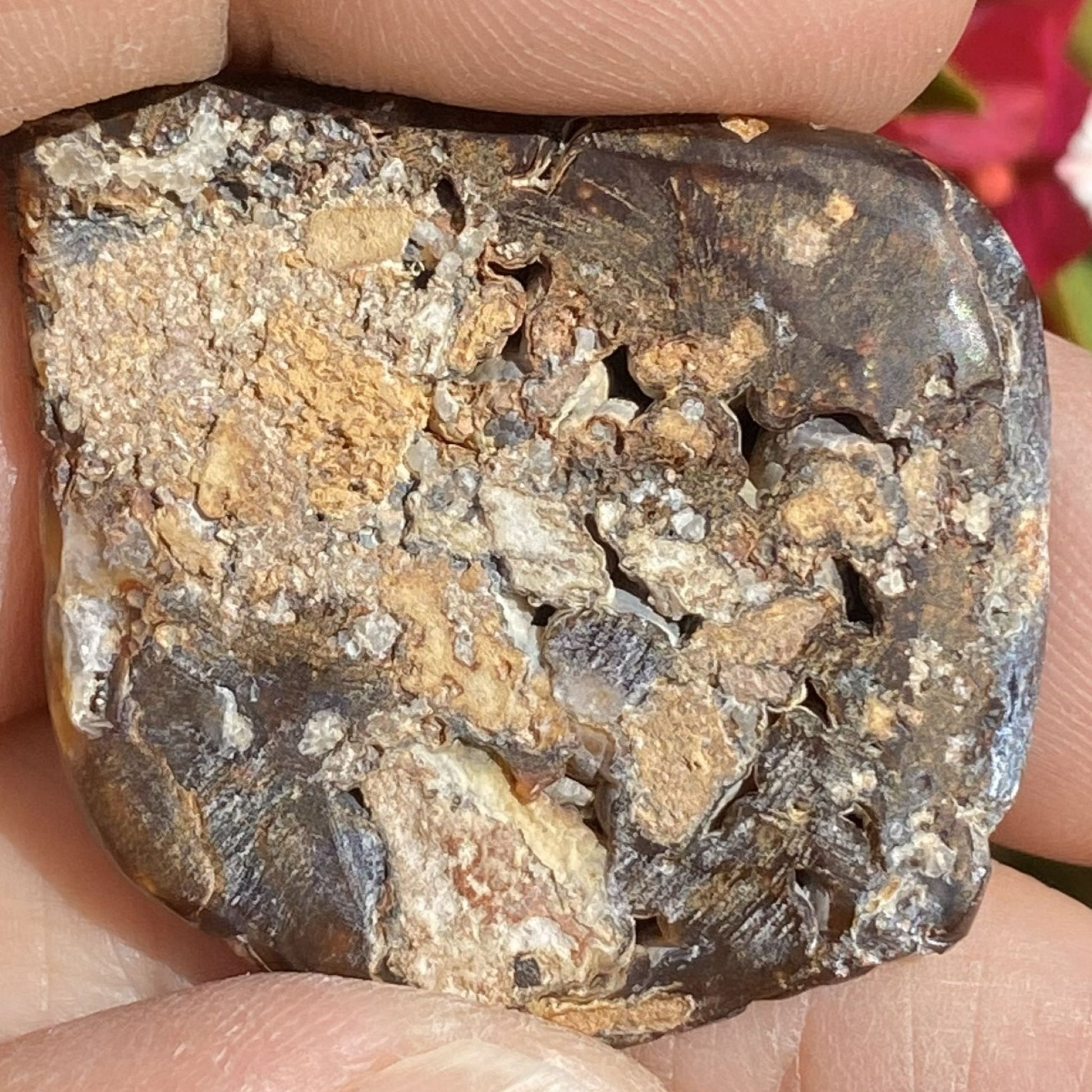 Close-up of a rough fire agate mineral stone held between fingers