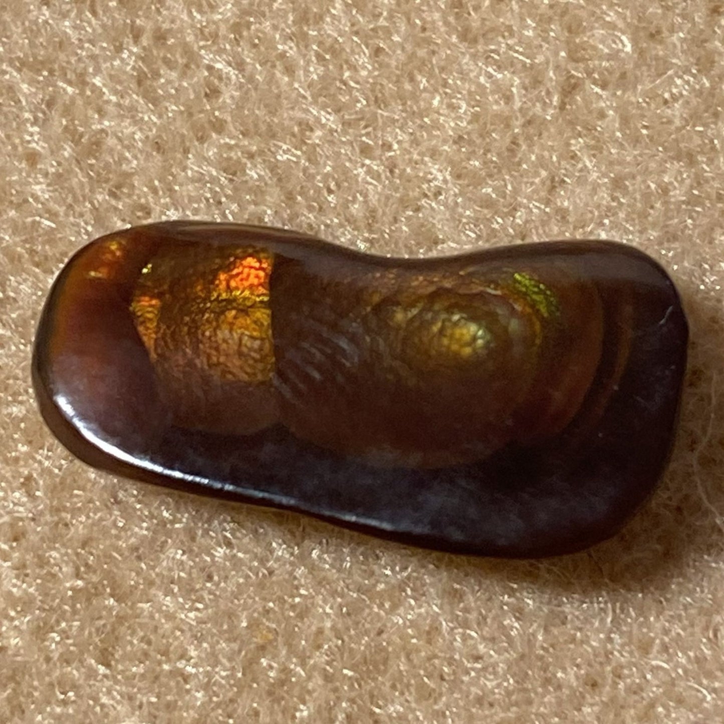 Slaughter Mountain Fire Agate Gemstone on a beige surface