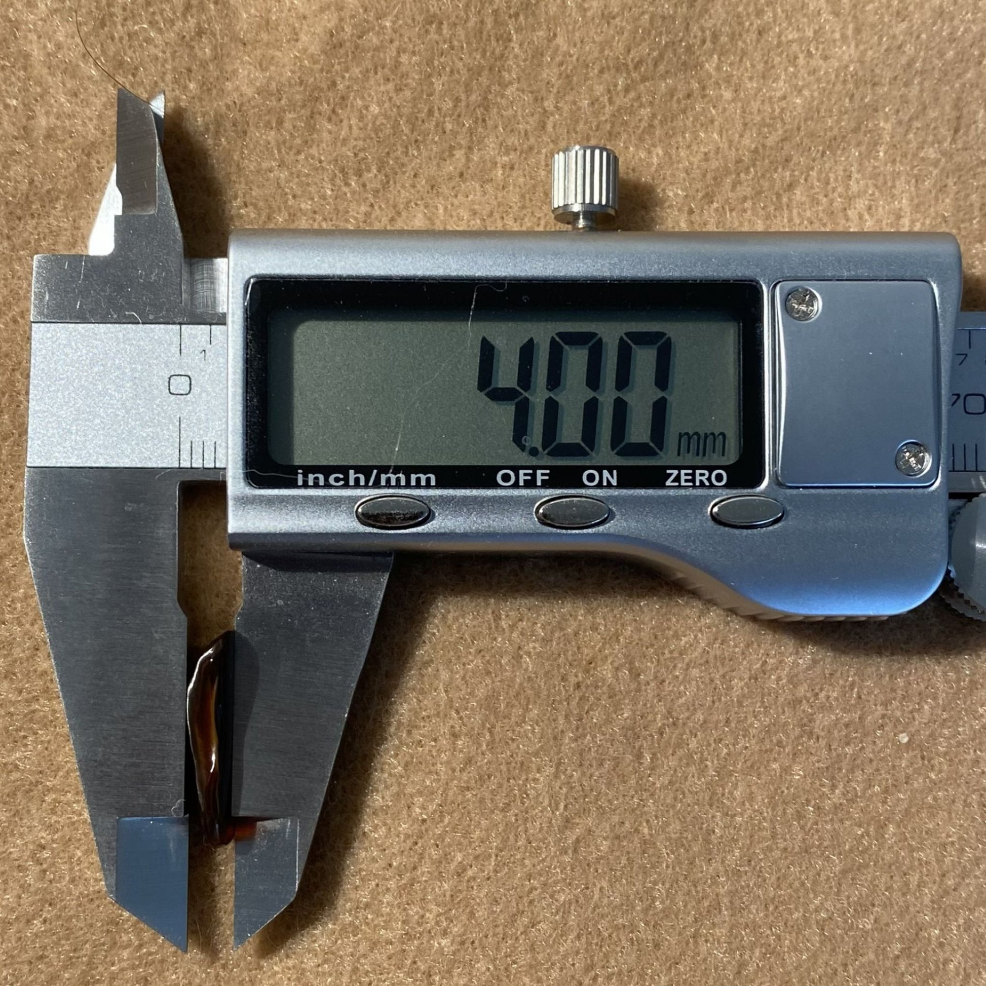 Digital caliper showing a measurement of 4.00 mm on a brown background