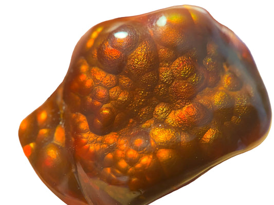 Close-up of a 50 carat polished Slaughter Mountain fire agate gemstone stone with a neutral white background.
