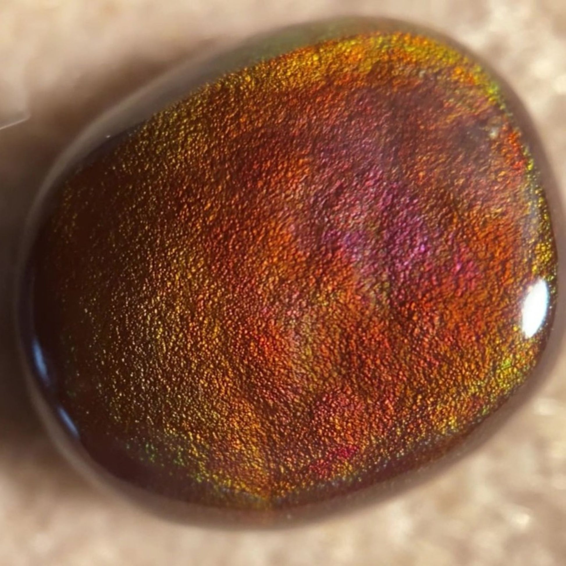 Close-up of a colorful, iridescent fire agate gemstone on a neutral background
