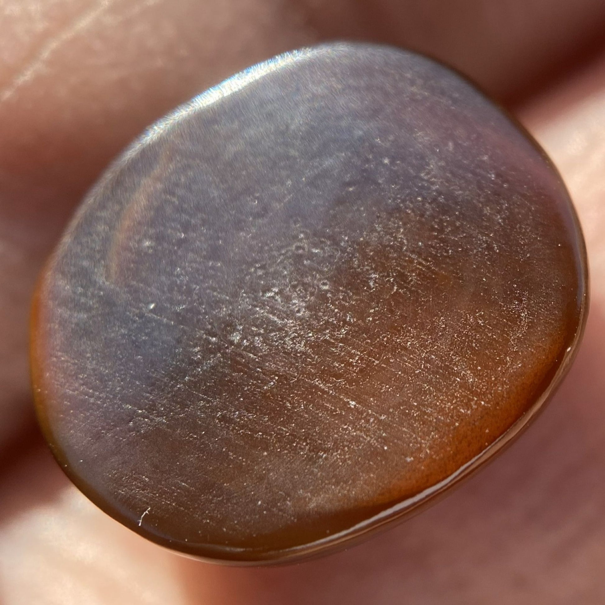 Close-up of the bottom of a fire agate gemstone held in hand