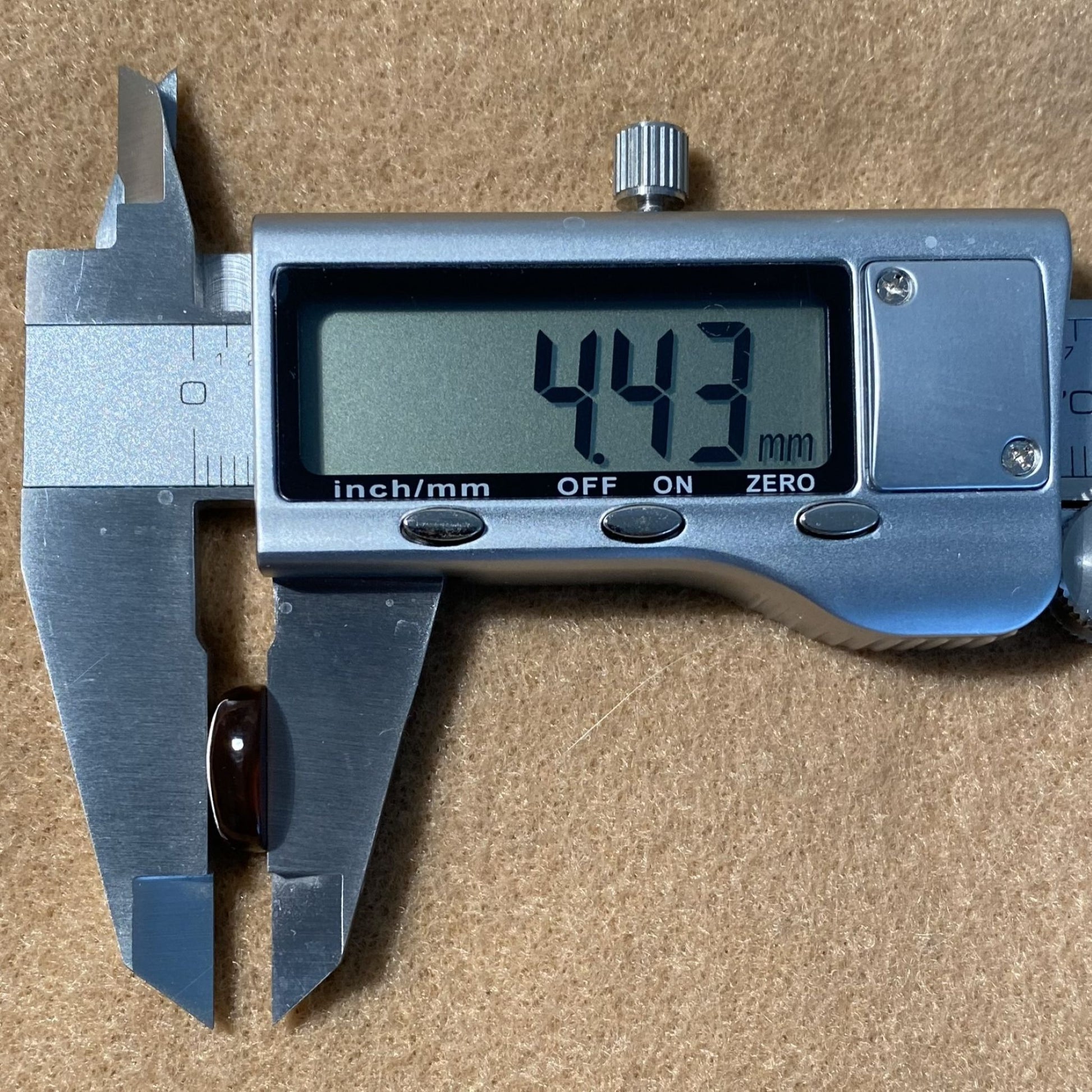 Digital caliper showing a measurement of 4.43 mm on a brown background