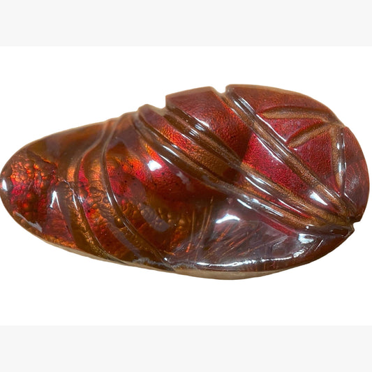 Close-up of a red colored Slaughter Mountain Fire Agate gemstone with carved grooves on a white background