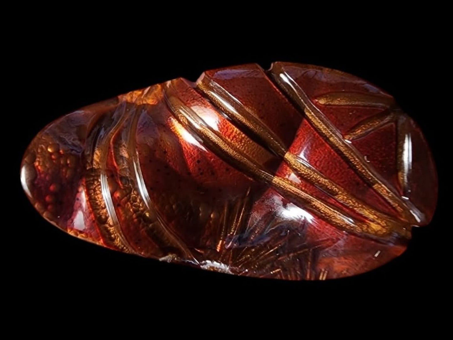 Decorative amber fire agate gemstone with intricate patterns on a black background