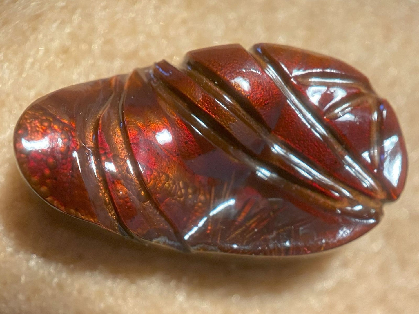 Polished amber fire agate gemstone on a beige background