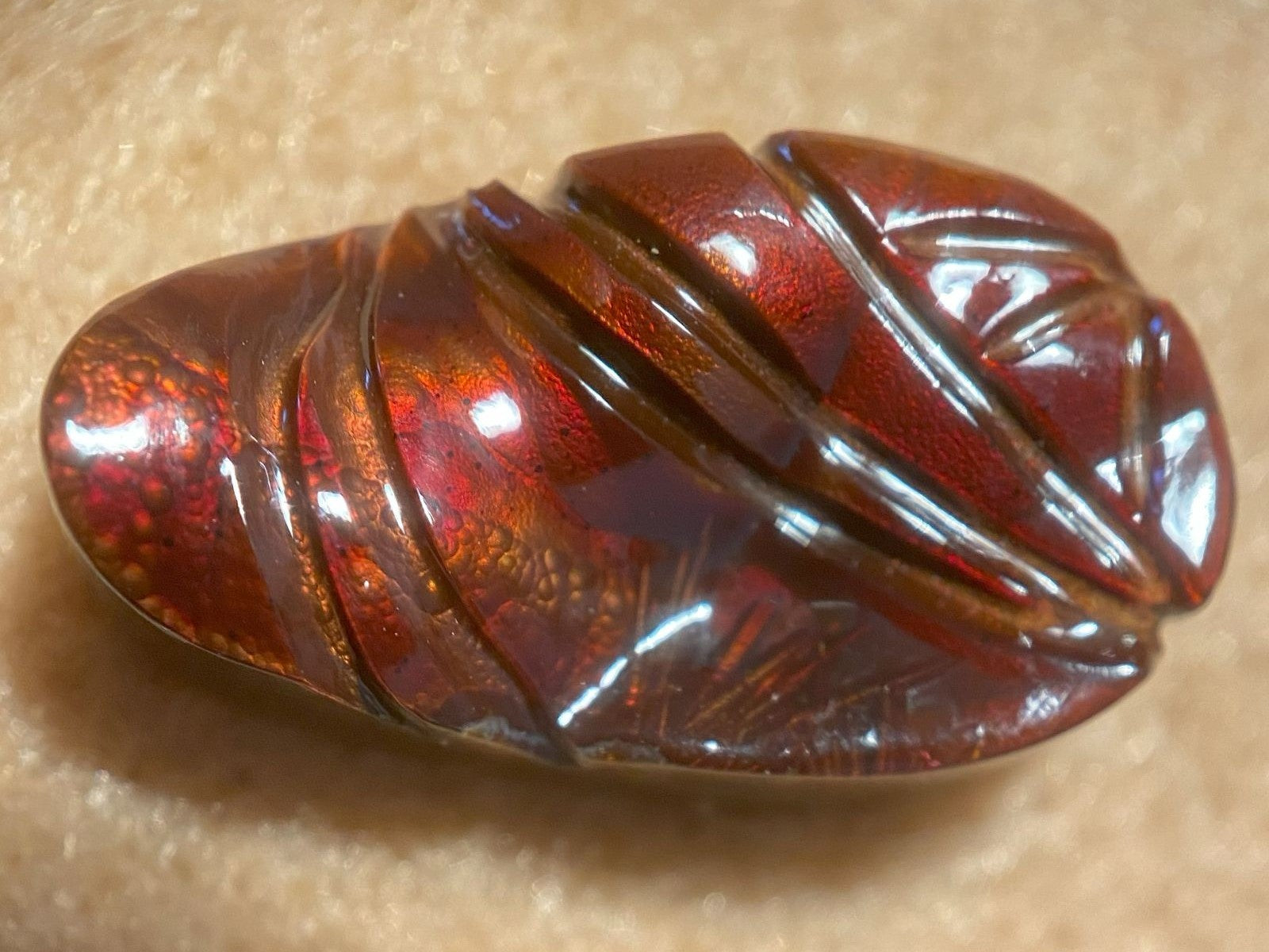Polished amber fire agate gemstone on a beige background
