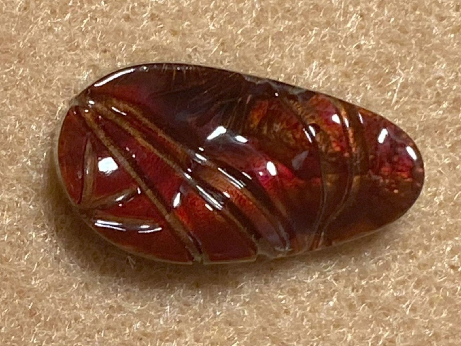 Polished red fire agate gemstone on a beige background