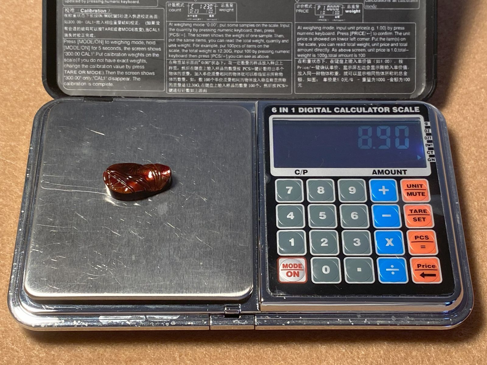 Calculator scale with a red fire agate gemstone on it, displaying a weight of 8.90 carats.