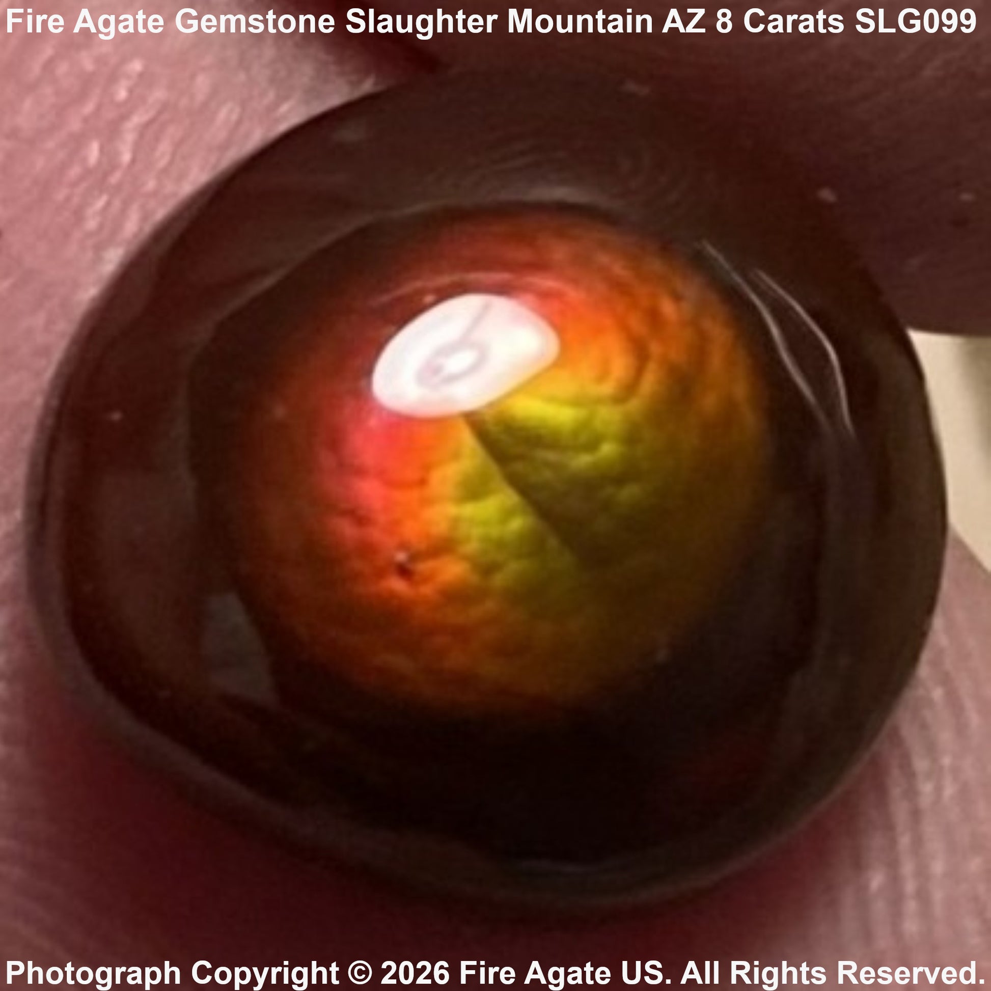 A 8-carat fire agate gemstone with a deep dark brown body and a vibrant fiery center showing orange, yellow, and red hues, resting on skin.