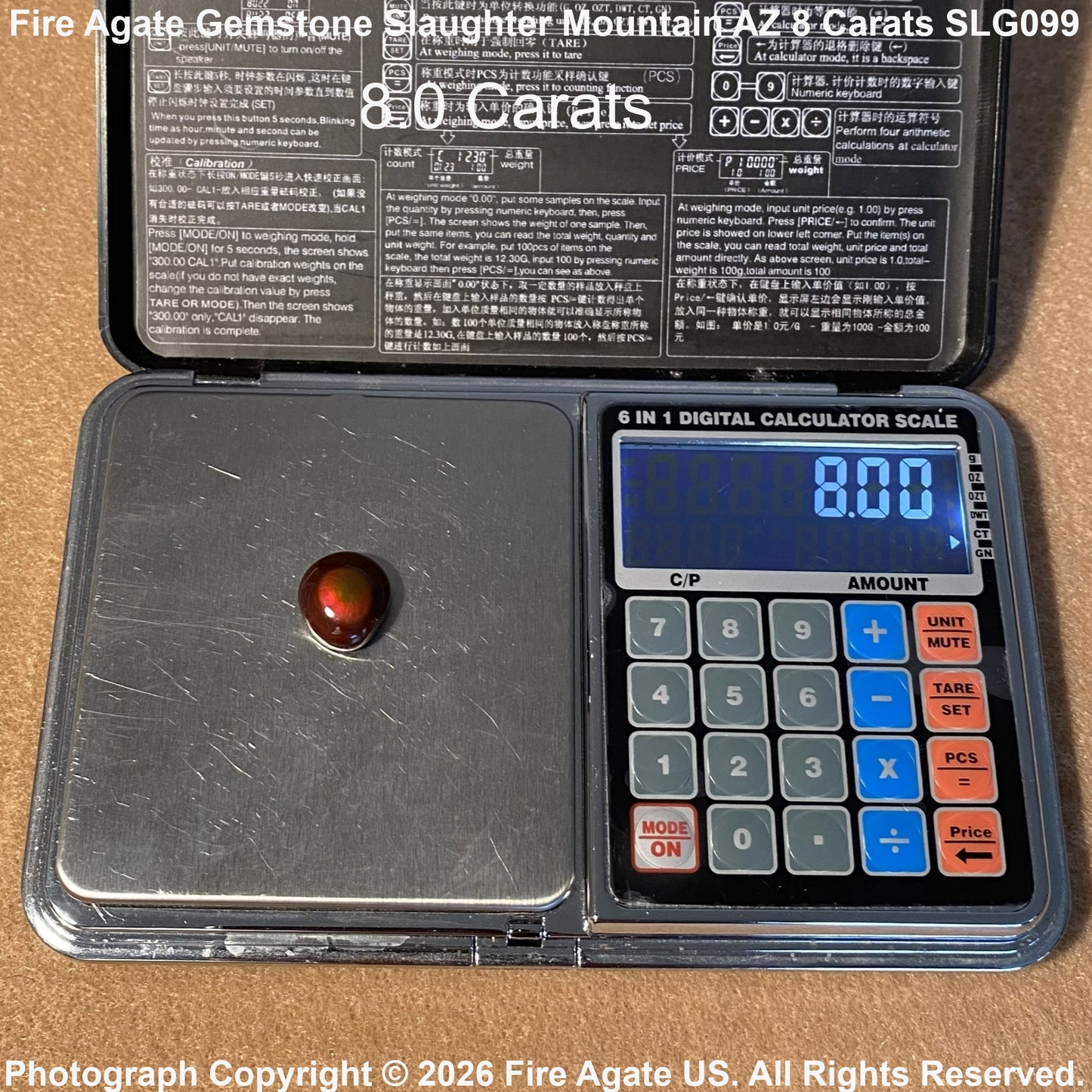 A 8.0 carat Fire Agate gemstone displayed on a digital scale inside its open black case, with product text overlays at the top and bottom.