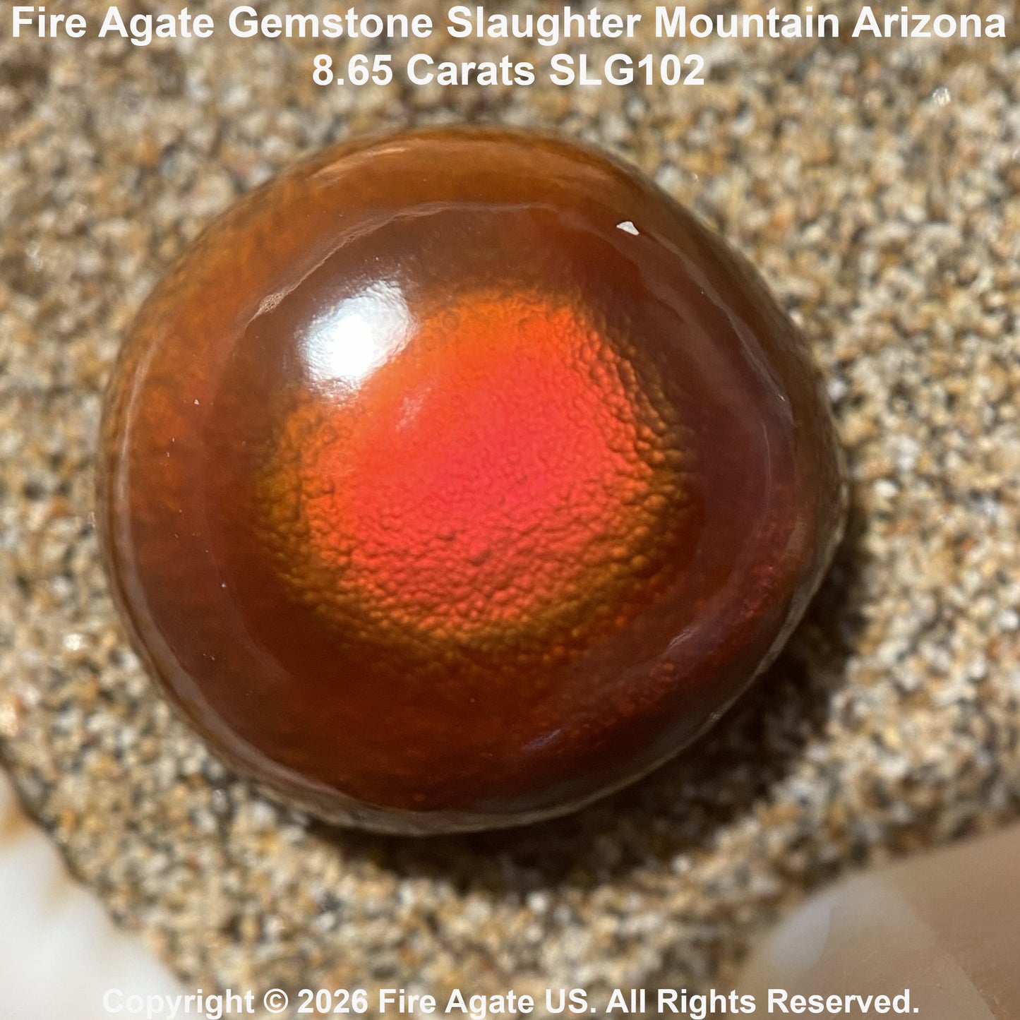 A polished fire agate gemstone with a vibrant red-orange center and dark brown outer ring, resting on a textured stone surface. Text overlays identify the stone as 'Fire Agate Gemstone Slaughter Mountain Arizona'.
