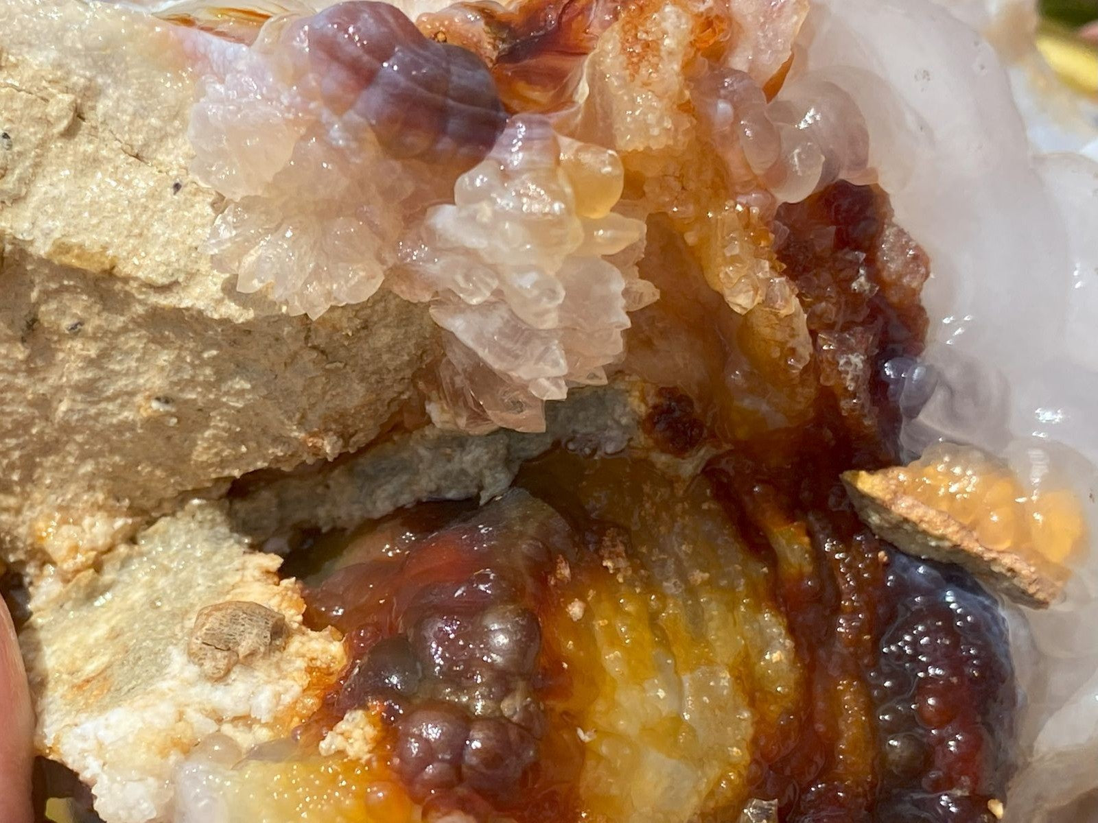 Close-up of fire agate mineral specimen with clear quartz crystals and colored chalcedony formations.