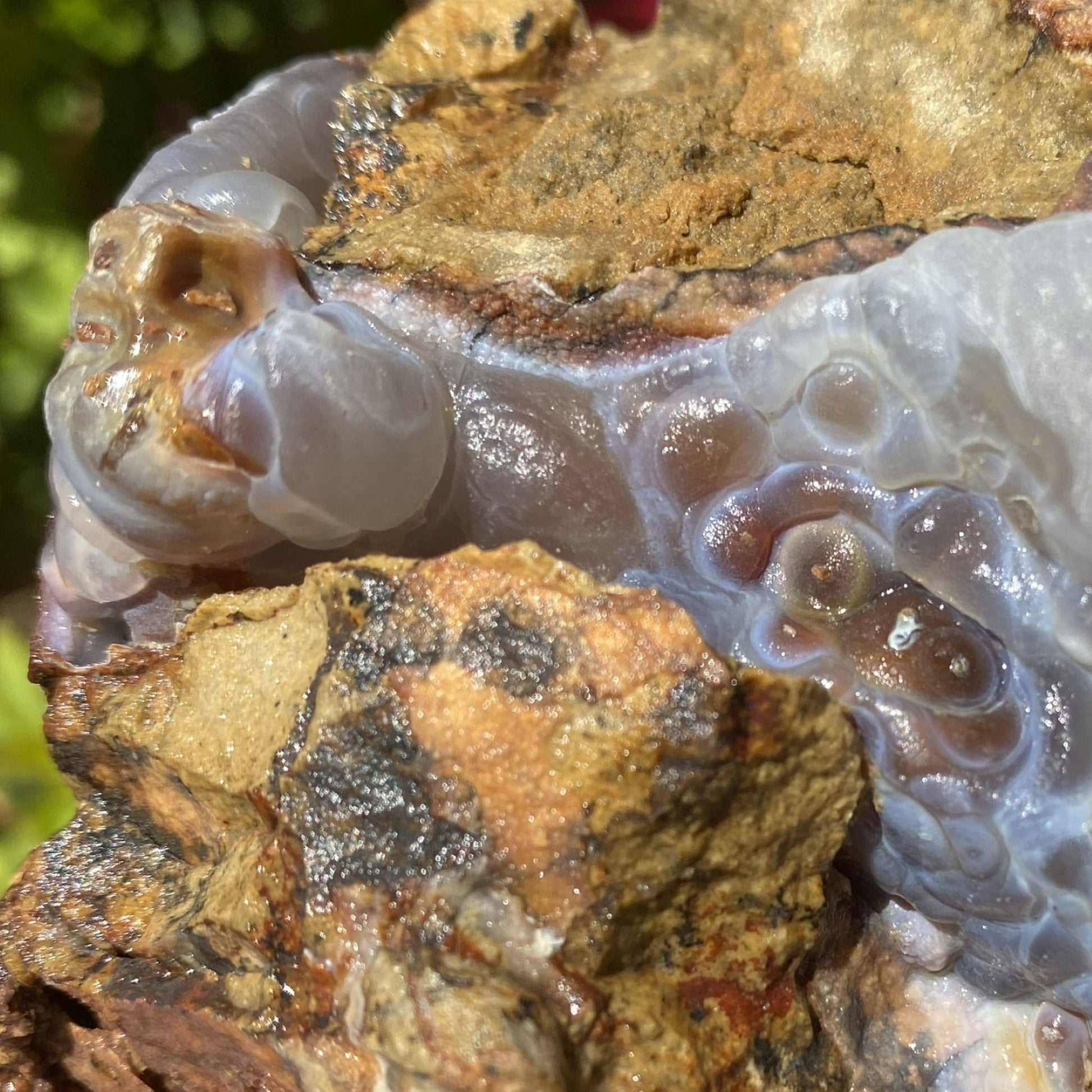 Close-up of a Slaughter Mountain Arizona Fire Agate Rough Mineral Specimen with crystal formation inside, surrounded by natural rock and earth.