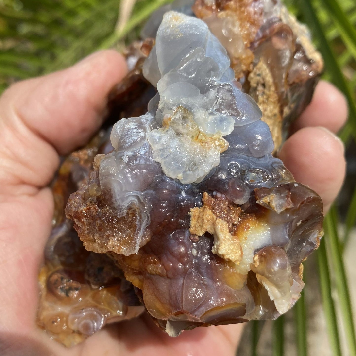 Hand holding a crystal rock with a natural background
