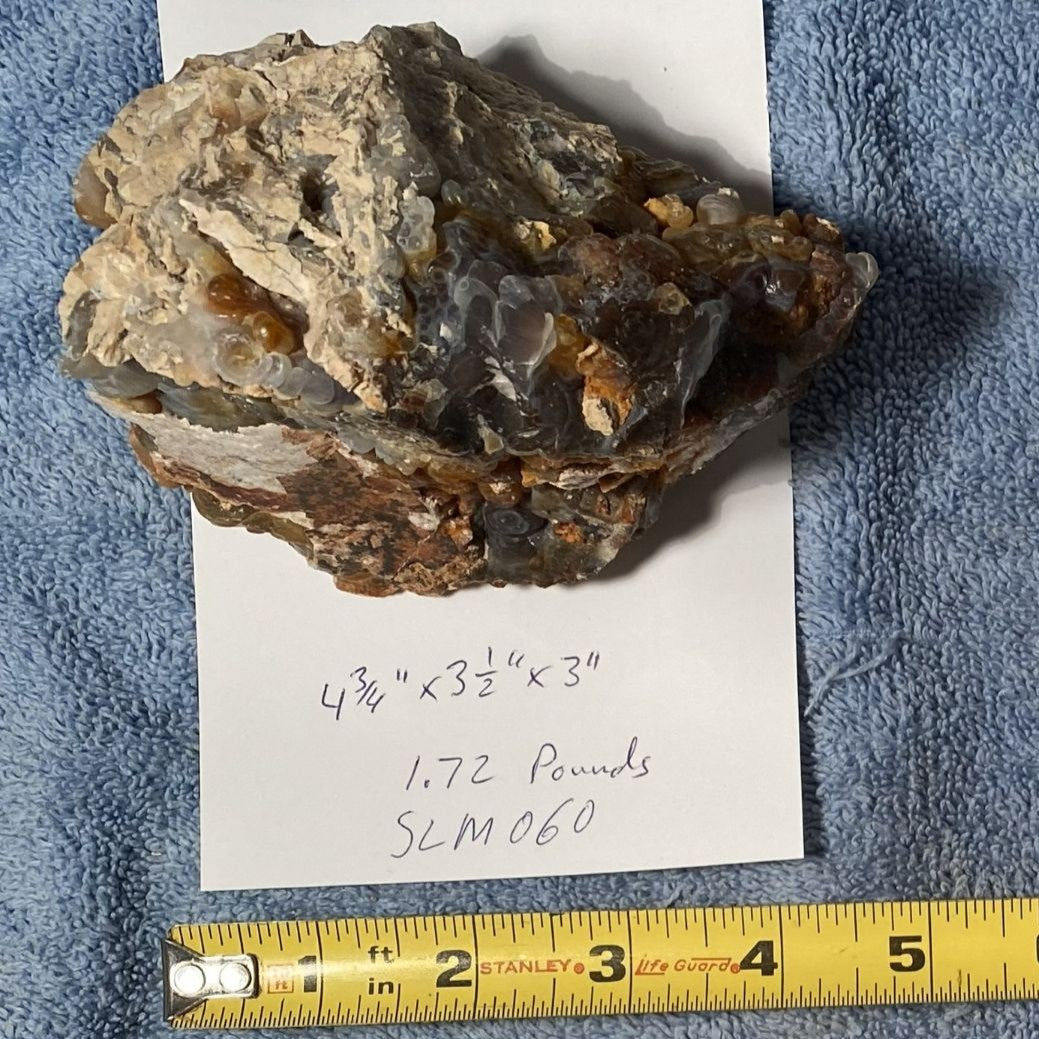 Mineral sample with crystal structure on a piece of paper, measured against a blue towel background.