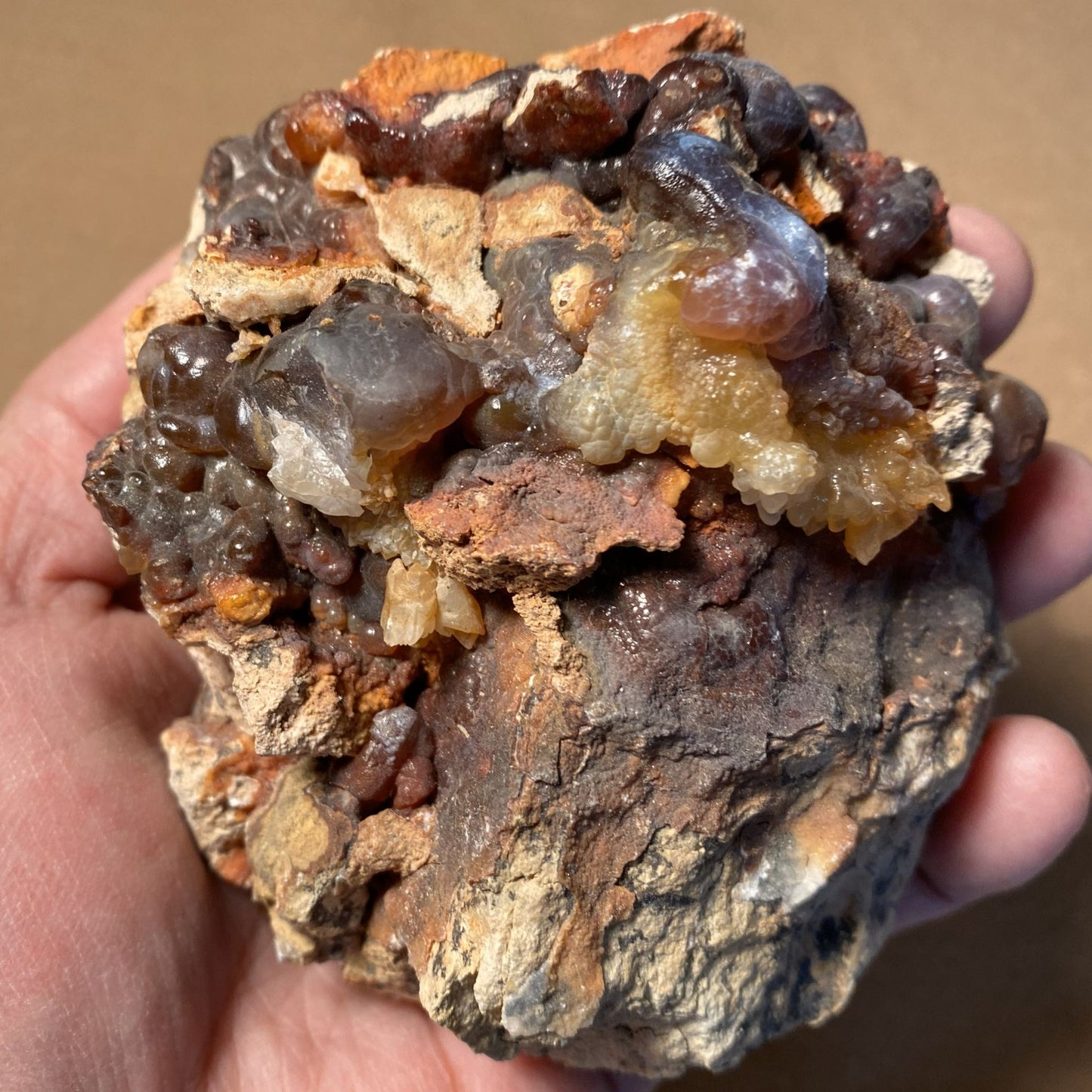 Hand holding a fire agate rough mineral rock with visible crystals