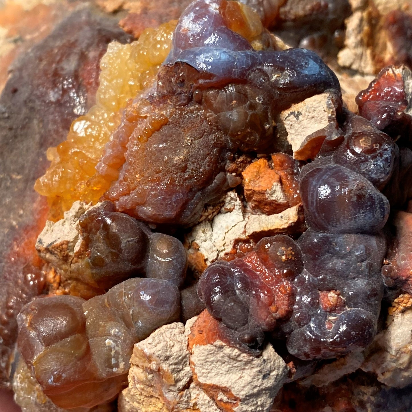 Close-up of a piece of high grade fire agate rough with other minerals and a brown and orange color palette.