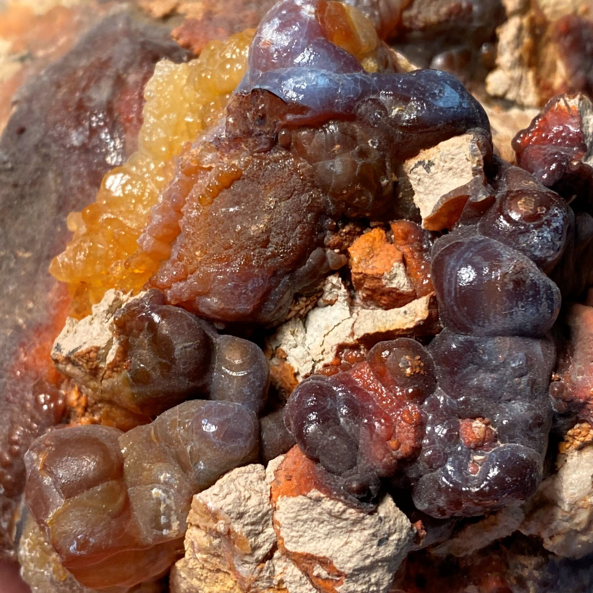 Close-up of a piece of high grade fire agate rough with other minerals and a brown and orange color palette.