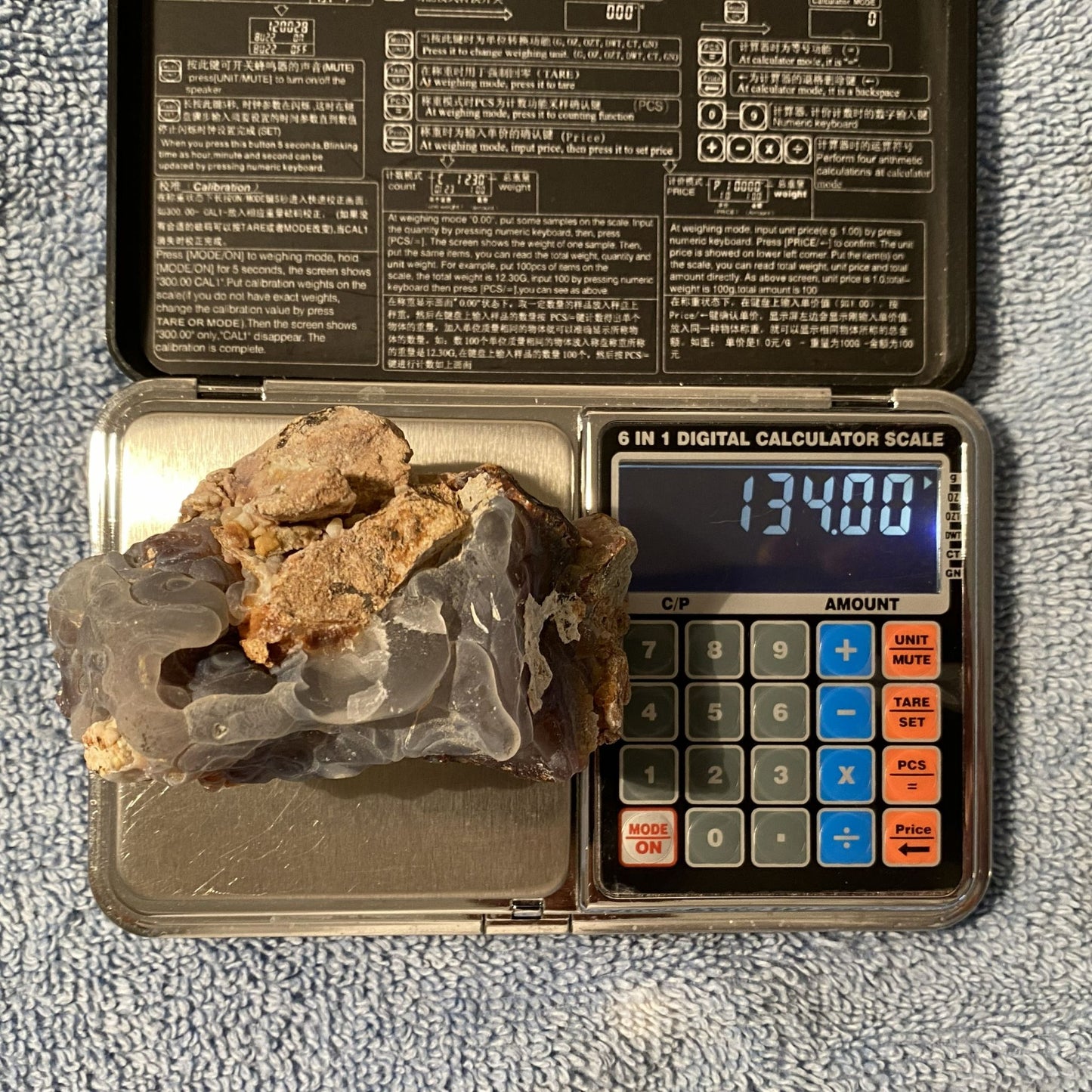 Digital calculator scale with a rock on top and digital display showing weight.