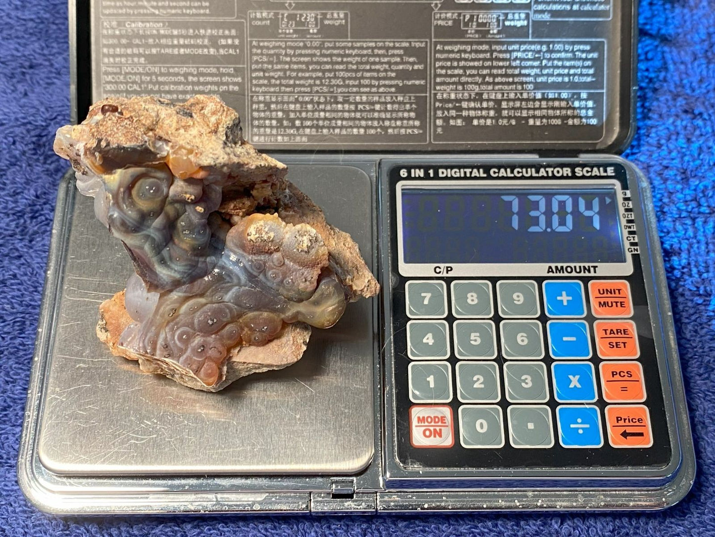 High Grade Slaughter Mountain Fire Agate Rough on a digital calculator scale with a blue background