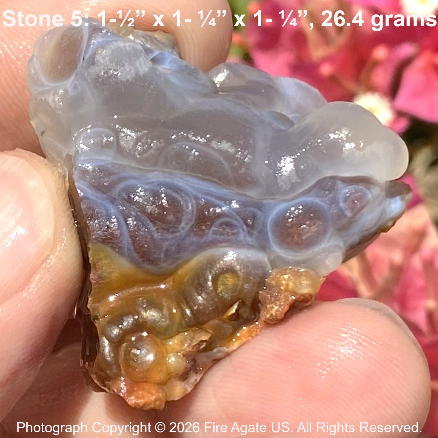 Close-up of a fire agate stone held between fingers with text overlay.