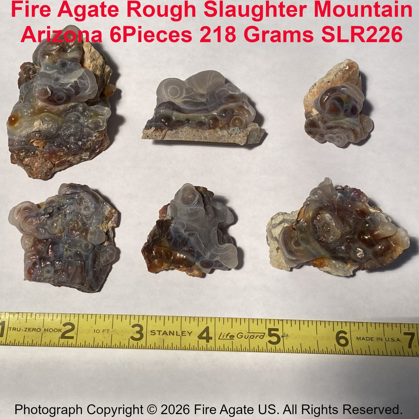 Slaughter Mountain Arizona Fire Agate Rough pieces with a measuring tape for scale on a white background.