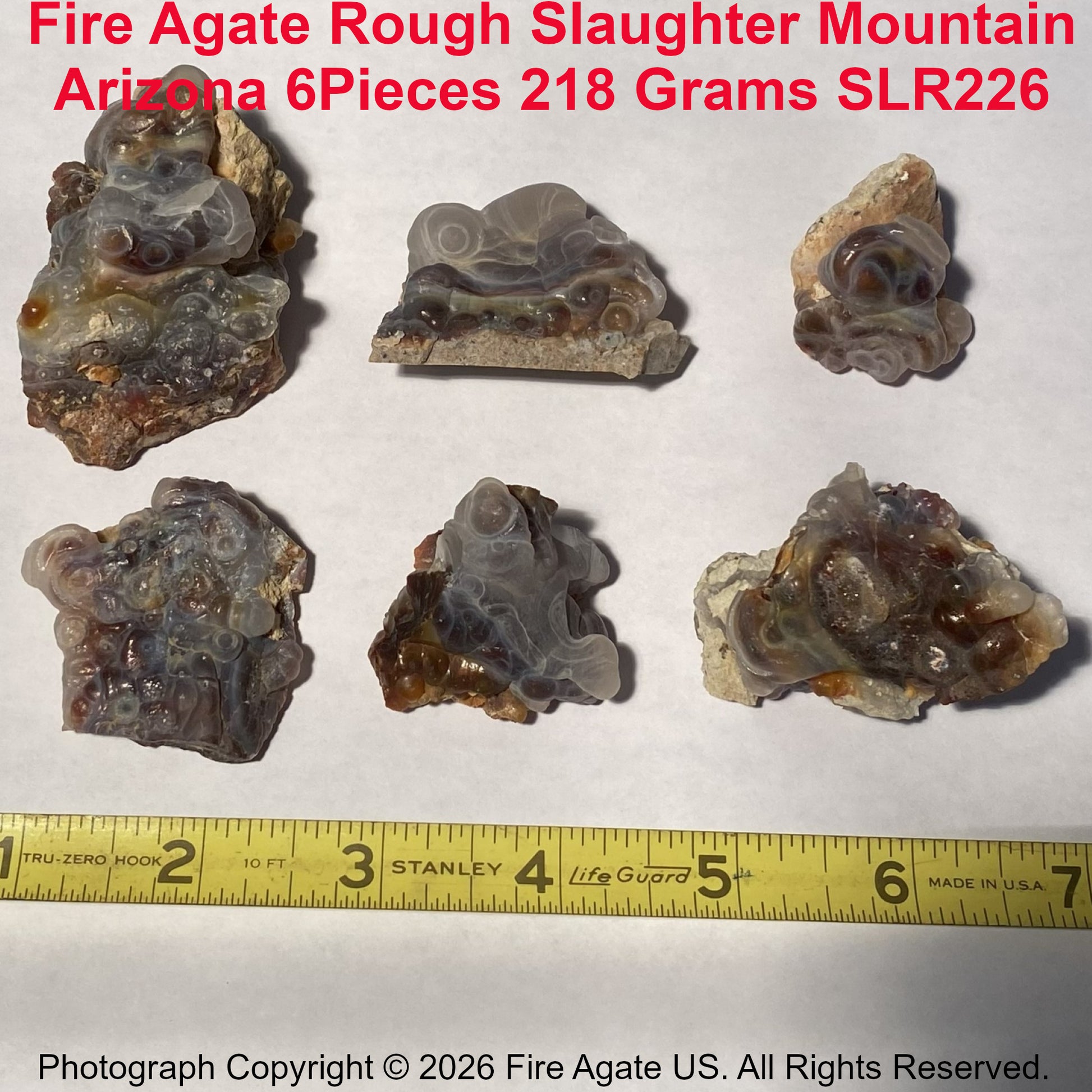 Slaughter Mountain Arizona Fire Agate Rough pieces with a measuring tape for scale on a white background.