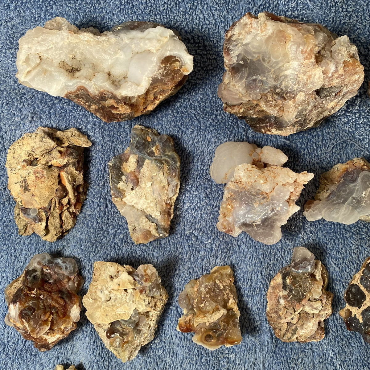 A group of rough natural fire agates arranged on a textured blue fabric background.